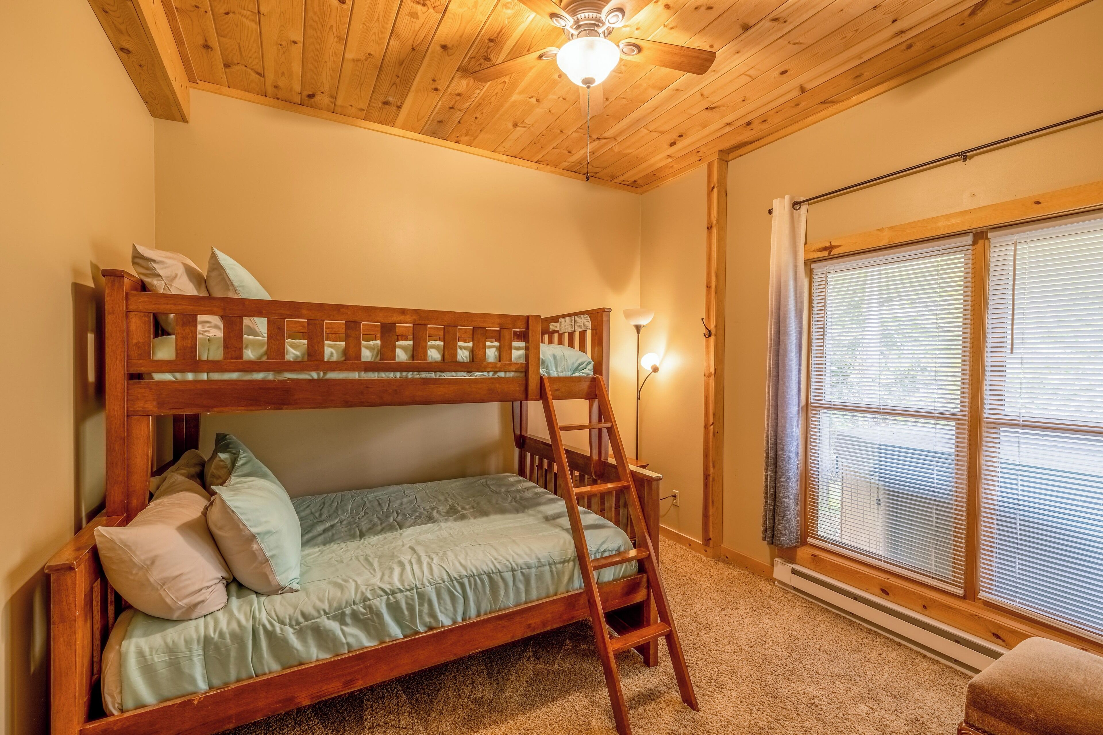 Una cama litera con escalera, una lámpara de pie y una ventana con persianas.