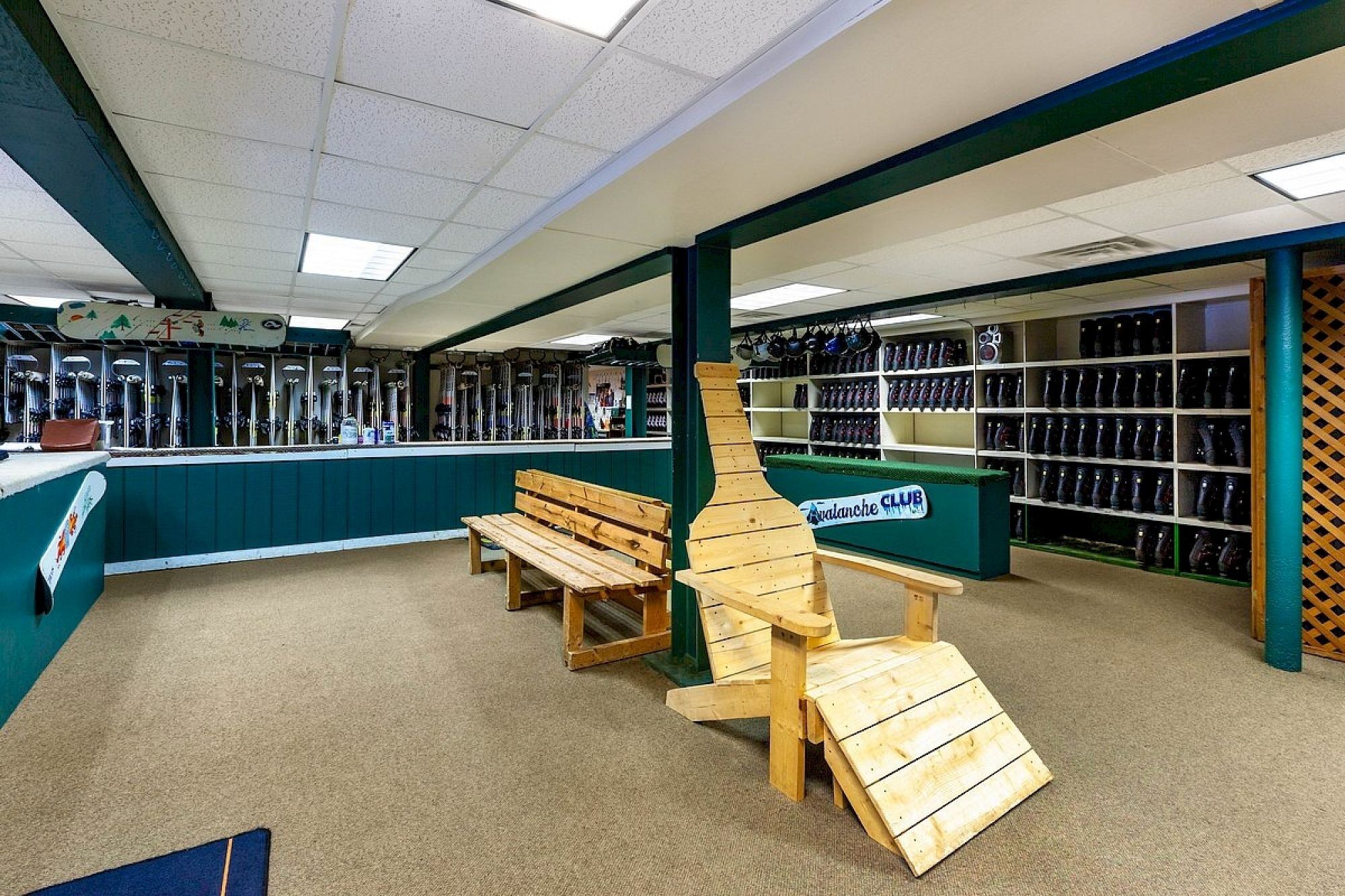 A ski rental shop interior with wooden benches, a wooden ski lift model, and shelves of skis and boots.