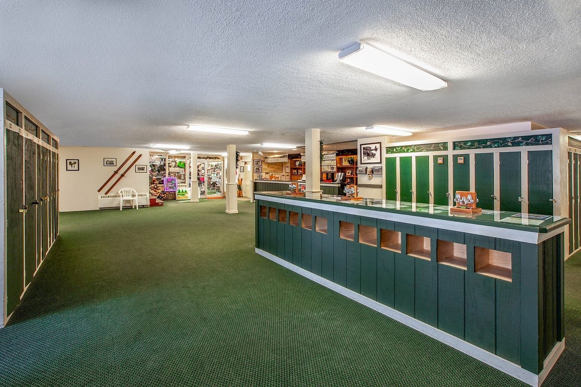A reception area with a green counter, lockers, and a staircase leading to another level.
