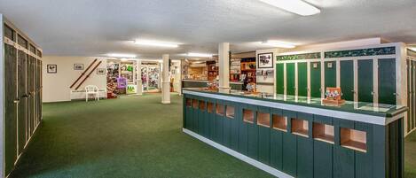 A reception area with a green counter, lockers, and a staircase leading to another level.