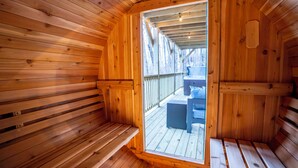 A wooden sauna with benches and a view of the outdoors.