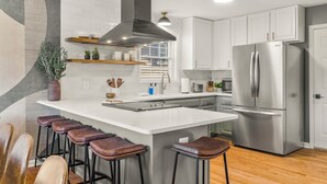 A modern kitchen with a large island, stainless steel appliances, and bar stools.