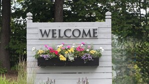 A wooden welcome sign with a flower planter below it.