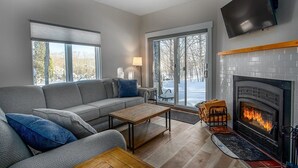 A modern living room with a fireplace, a sofa, a coffee table, and a TV mounted on the wall.