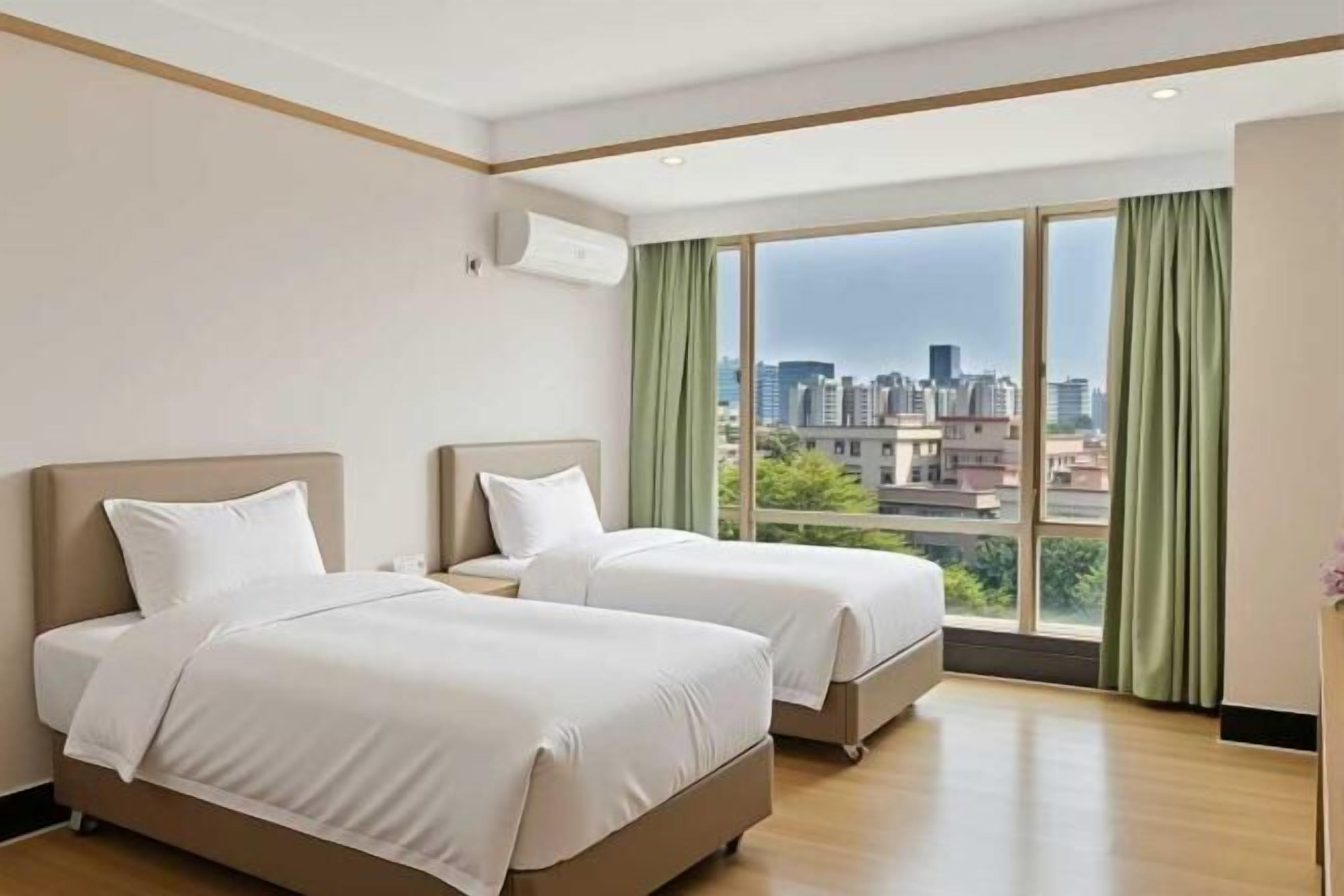 Habitación de hotel con dos camas, un ventanal grande con vistas a la ciudad y un diseño moderno.