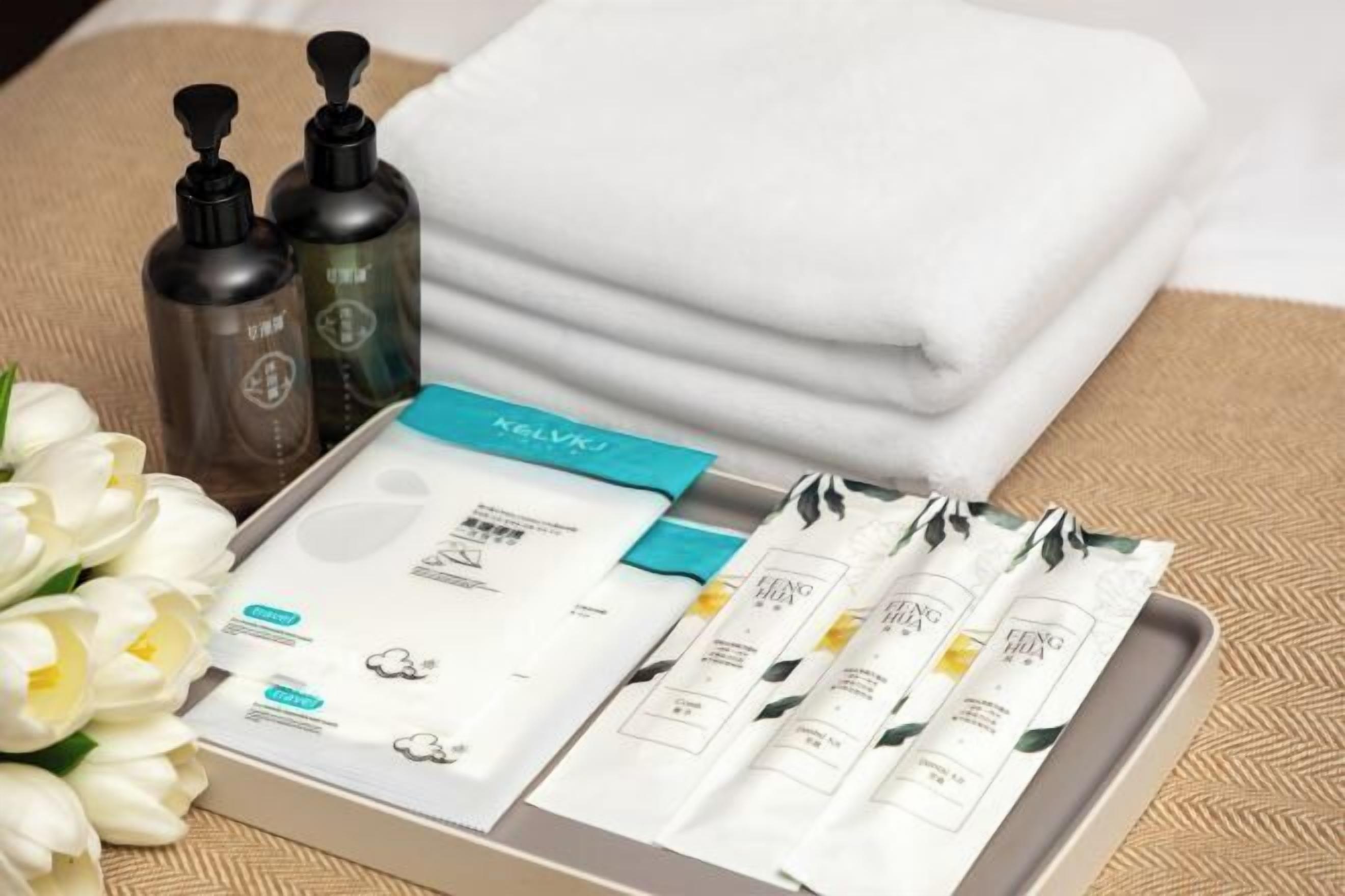 A tray with toiletries, a folded towel, and a bouquet of white flowers.