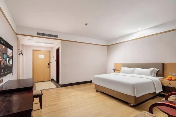 A hotel room with a bed, bedside table, chair, and a small table with fruit. - Joy Hotel (Foshan Nanhai Pengruili Jihua Plaza) (Foshan)