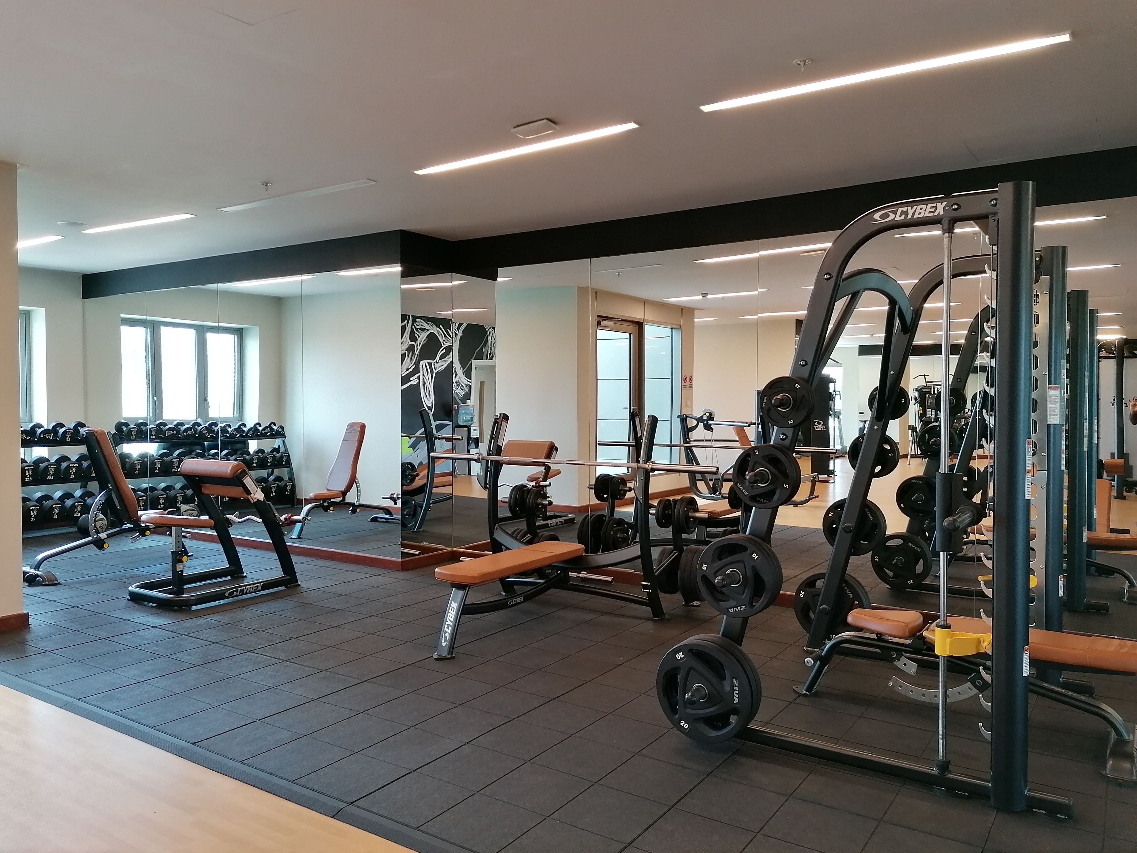 Een sportschool met gewichthefapparatuur, banken en halters.