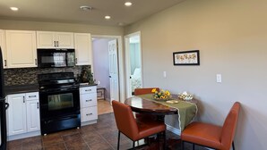 A kitchen with white cabinets, a black stove, and a dining area with a table and two chairs.