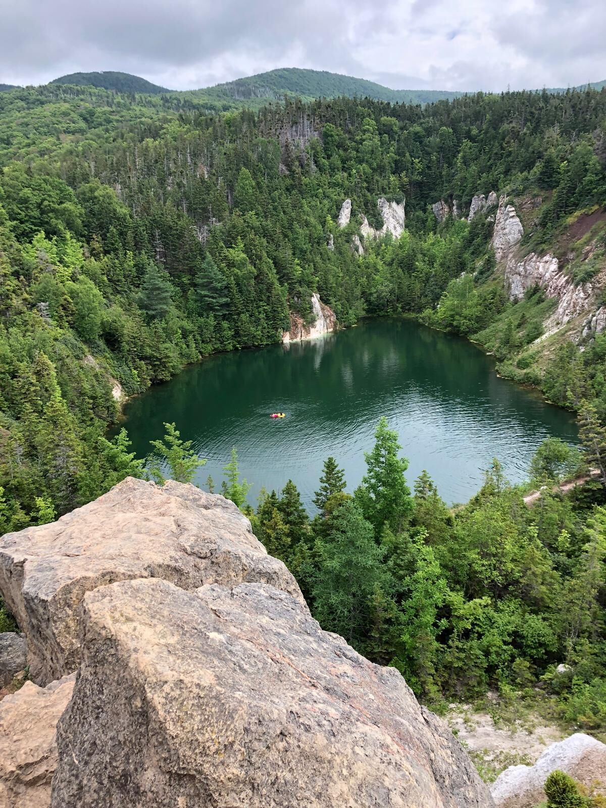 Un lago rodeado de un bosque denso y acantilados rocosos.