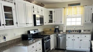A modern kitchen with white cabinets, granite countertops, a stainless steel stove, and a dishwasher. - Charming 3-bedroom condo with AC, WiFi in brilliant Wildwood Crest (Wildwood Crest)