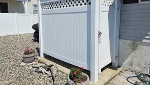 A white wooden fence with a lattice top, a potted plant, and a hose on the ground. - Charming 3-bedroom condo with AC, WiFi in brilliant Wildwood Crest (Wildwood Crest)