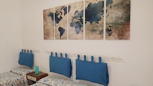 A room with two beds, a world map artwork, and a simple decor.