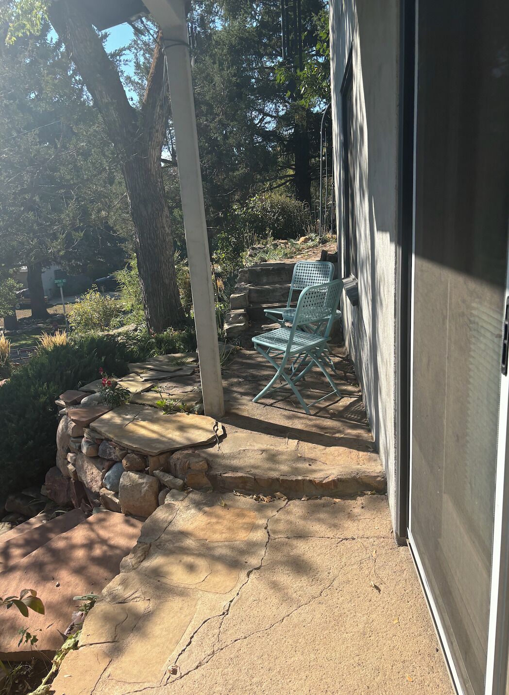 A patio with stone steps leading to a seating area with two chairs.