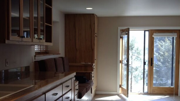 A kitchen with wooden cabinets, a countertop, and a sliding glass door leading to a balcony.