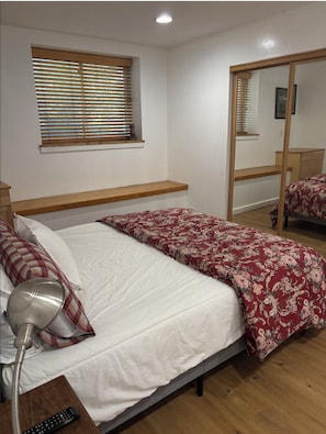 Quarto com cama, abajur e janela com persianas.