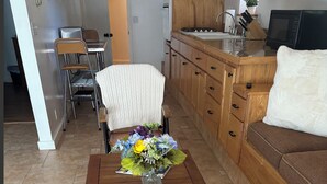 A wooden coffee table with a vase of flowers in the center, a chair, and a sofa in a living room.