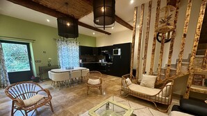 A spacious living area with a dining table, wicker chairs, a glass coffee table, and a staircase with a wooden railing. - La villa verte Domaine de la tapie de Bouchet - in the Camargue (Arles)