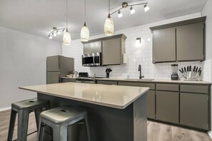 A modern kitchen with a central island, stainless steel appliances, and pendant lighting.