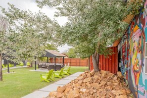 A backyard with a covered patio, outdoor seating, a stone wall, and a colorful mural.