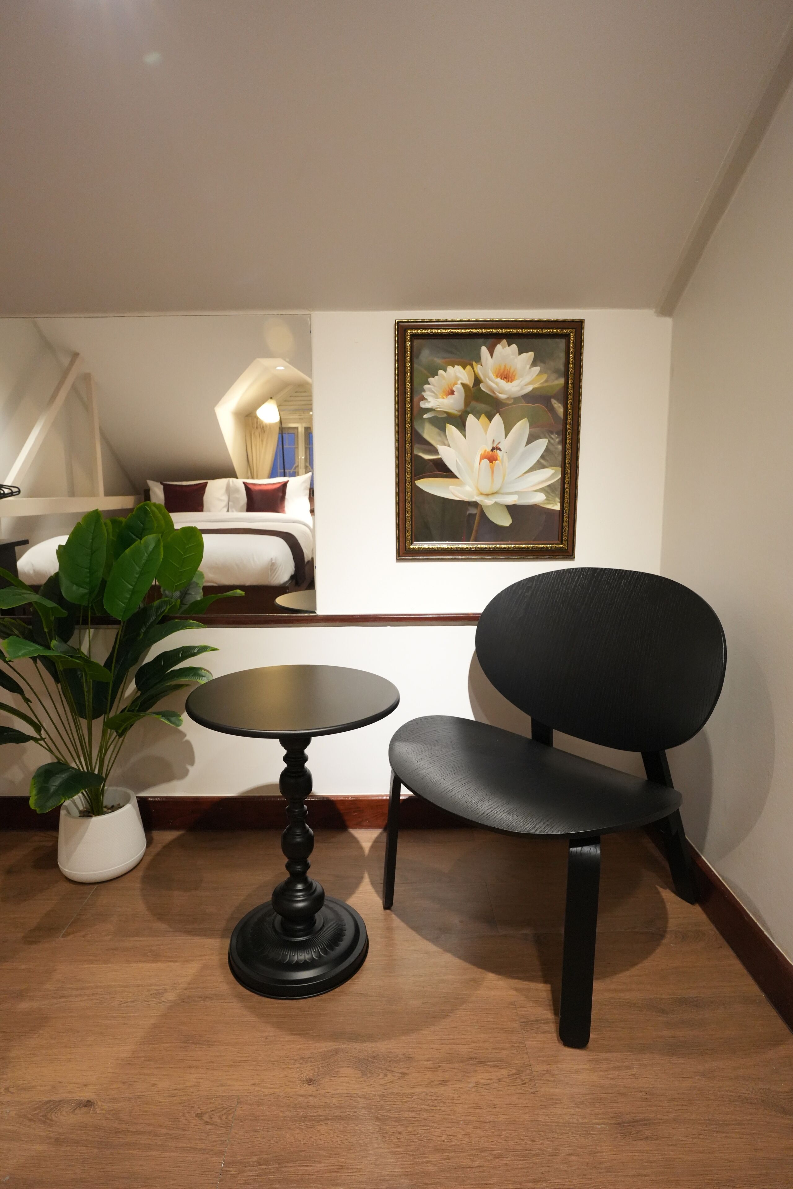 A room with a black chair, a small round table, and a potted plant.