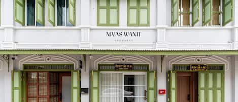 A hotel facade with green shutters, a sign reading "NIVAS WANIT YAWARAT," and two doors labeled "HOTEL" and "HOTEL (PRIVATE)".