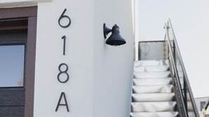 Un escalier avec une rampe, un luminaire fixé au mur et un panneau indiquant le numéro « 618A » sur un mur blanc.