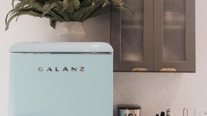 Une cuisine avec un réfrigérateur Galanz bleu clair, une machine à café et un bloc à couteaux posé sur le plan de travail.
