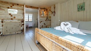 A rustic room with a bed, a radiator, a wooden wall, and a mirror. - Camber Beach House - Five Bedroom Villa, Sleeps 10 (Camber)