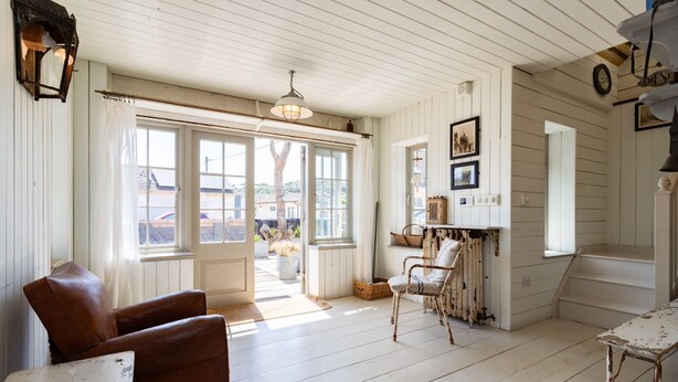 A rustic interior with a wooden floor, a brown leather chair, a wicker chair, and a table. - Camber Beach House - Five Bedroom Villa, Sleeps 10 (Camber)
