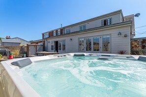 Ein zweistöckiges Haus mit Whirlpool im Garten.