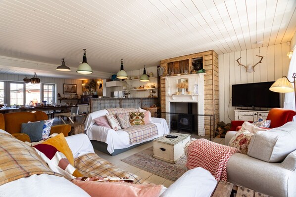 Una sala de estar acogedora con chimenea, televisor y comedor con muebles de madera.