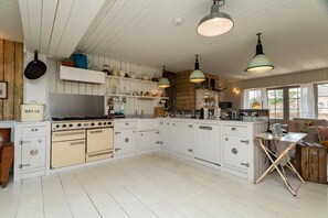 A kitchen with white cabinets, a stove, and hanging lights.