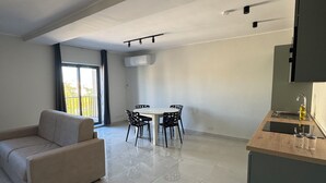 Una sala de estar moderna con sofá, mesa de comedor, sillas y una zona de cocina con pileta y mostrador.