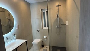 Un baño moderno con ducha acristalada, lavabo blanco y retrete.
