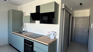 Una cocina moderna con horno empotrado, microondas y hervidor, armarios azul claro y encimera de madera.