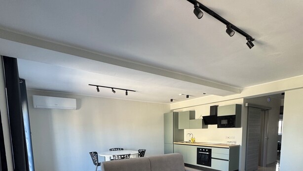 Una sala de estar moderna con un sofá, una mesa de centro y una zona de cocina al fondo.