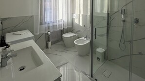 Un baño moderno con un espejo grande, una bañera, una ducha y un lavabo.