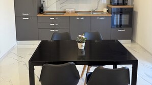 Una cocina moderna con armarios oscuros, una mesa de comedor negra y dos sillas.