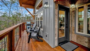 Eine Holzterrasse mit Sitzgelegenheiten im Freien, einem überdachten Bereich und Blick auf den umliegenden Wald.