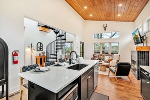 A modern kitchen with a central island, a staircase, and a cozy living area with a fireplace. - Location, Location, Location! New Hidden Gem - Close to All the Top Attractions! (Pigeon Forge)
