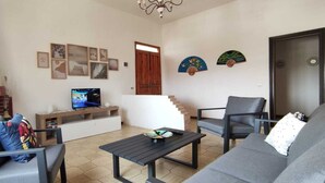 Una sala de estar con chimenea, televisor, escalera y puerta.