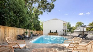Un cortile con piscina, mobili in vimini e una recinzione in legno.