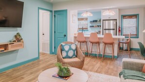 Un soggiorno moderno con zona pranzo, cucina e TV a parete.