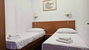 A hotel room with two single beds, a wooden headboard, two bedside lamps, and a framed map on the wall. - Three-bedroom apartment with balcony (Dubrovnik)