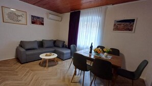 A living room with a sofa, a dining table with chairs, a coffee table, and artwork on the walls. - Three-bedroom apartment with balcony (Dubrovnik)