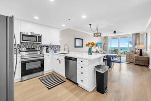 Une cuisine moderne avec des meubles blancs, des appareils en acier inoxydable et un îlot central.