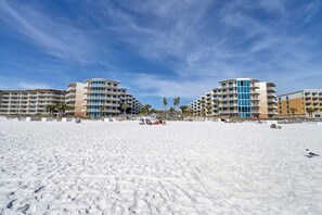Un hôtel en bord de mer doté de nombreux balcons, d’une plage de sable et de palmiers.
