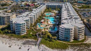 Un complexe hôtelier comprenant plusieurs immeubles de grande hauteur, un espace piscine central et une plage.