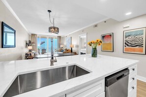 A modern kitchen with a large island, stainless steel sink, and a dishwasher.
